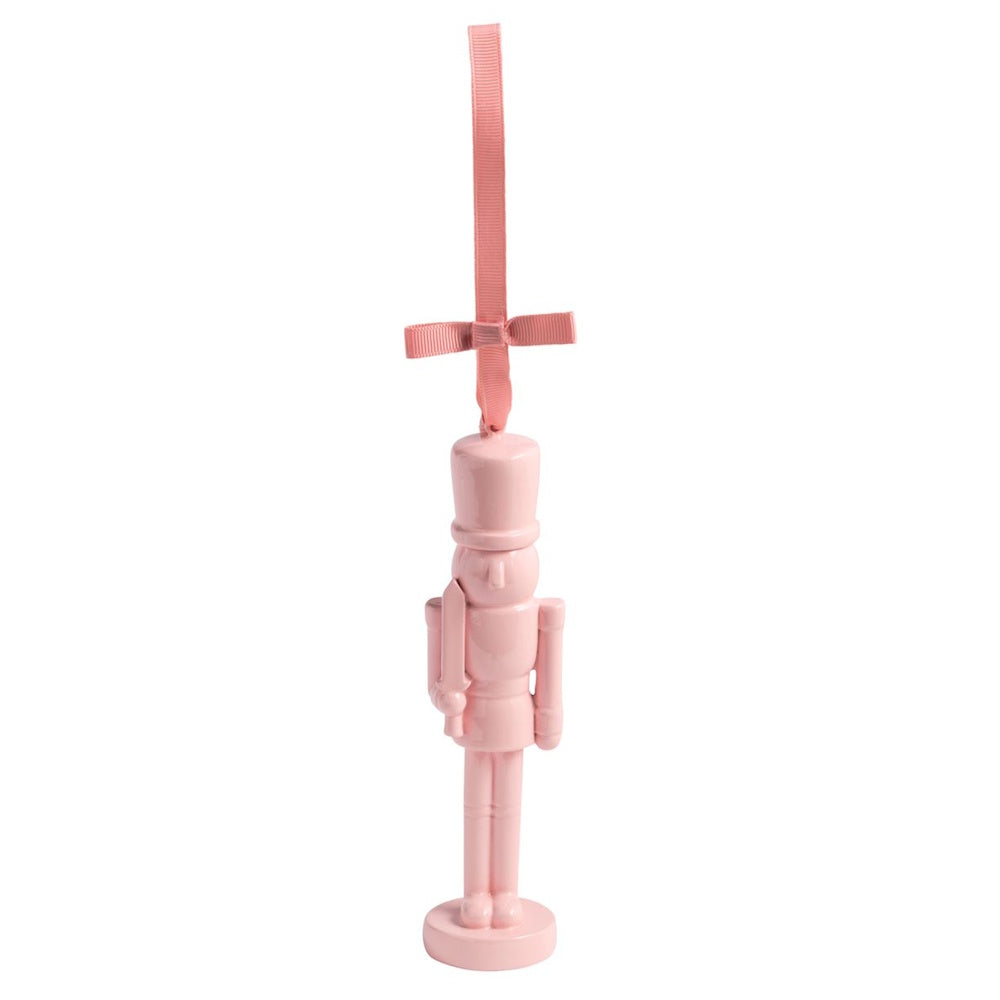 Glossy pastel pink nutcracker Christmas ornament hanging from a matching pink ribbon.