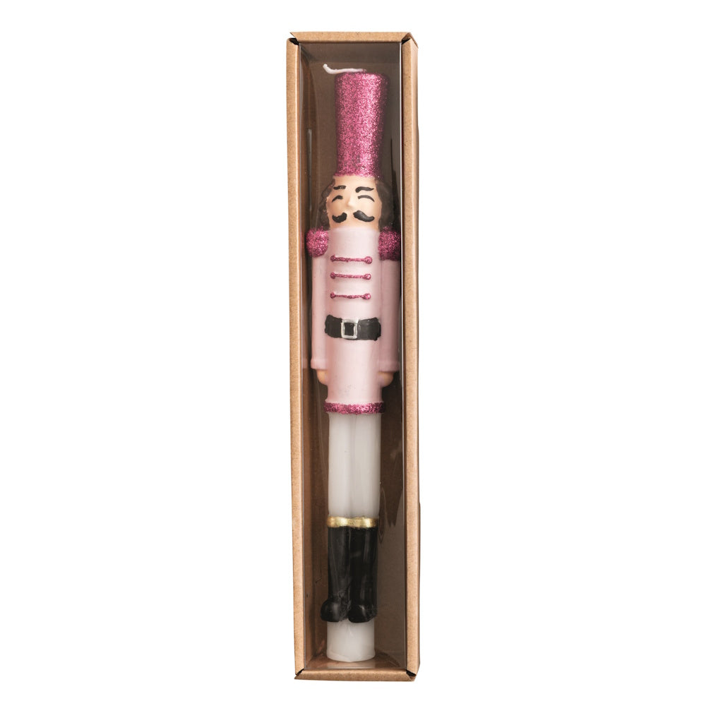 Front view of a pink and white wax nutcracker taper candle with glitter details in a boxed package.
