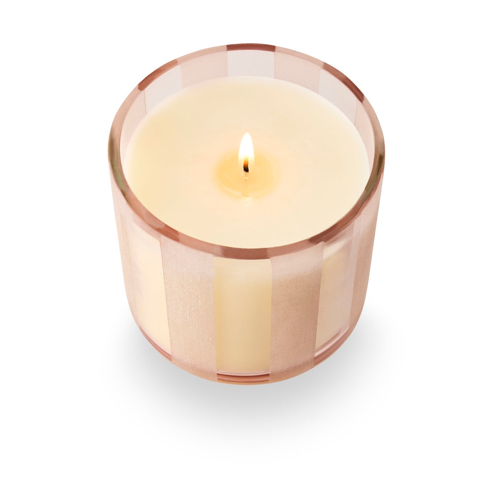 Top-down view of a lit candle in a translucent pink etched-stripe glass jar.