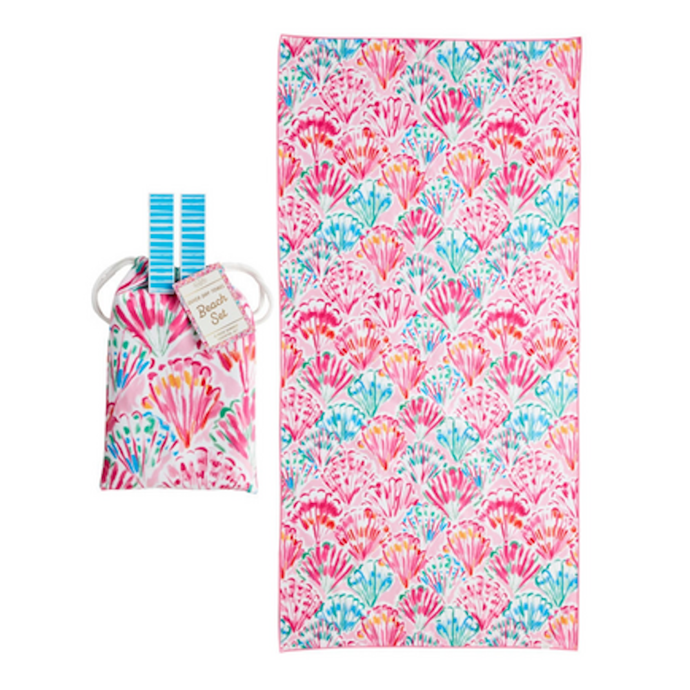 A pink quick-dry beach towel and matching pouch with a colorful seashell pattern and blue clips.