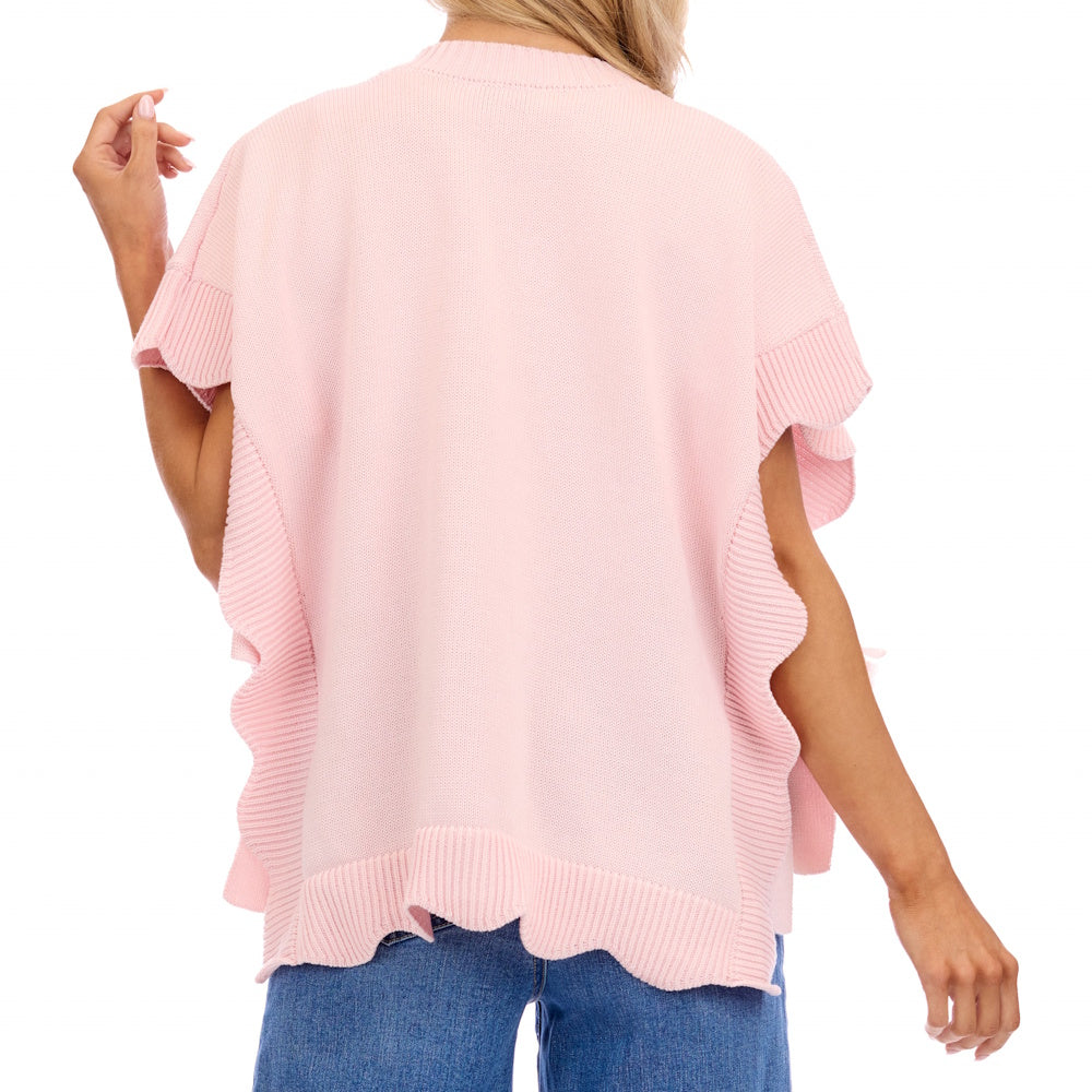 Back view of a woman wearing a light pink, short-sleeved knit sweater with ruffled sides and a scalloped hem.