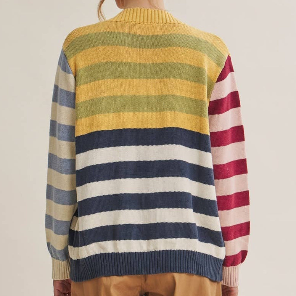 Back view of model wearing a colorblock multi-stripe knit cardigan with mixed yellow, navy, blue, and red patterns.