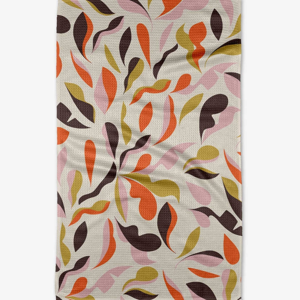 Waffle-weave kitchen towel featuring a dense pattern of abstract, colorful autumn leaves.