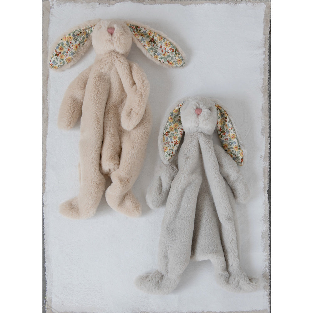 Two plush bunny comforter toys, one beige and one grey, with floral-patterned inner ears on a white blanket.