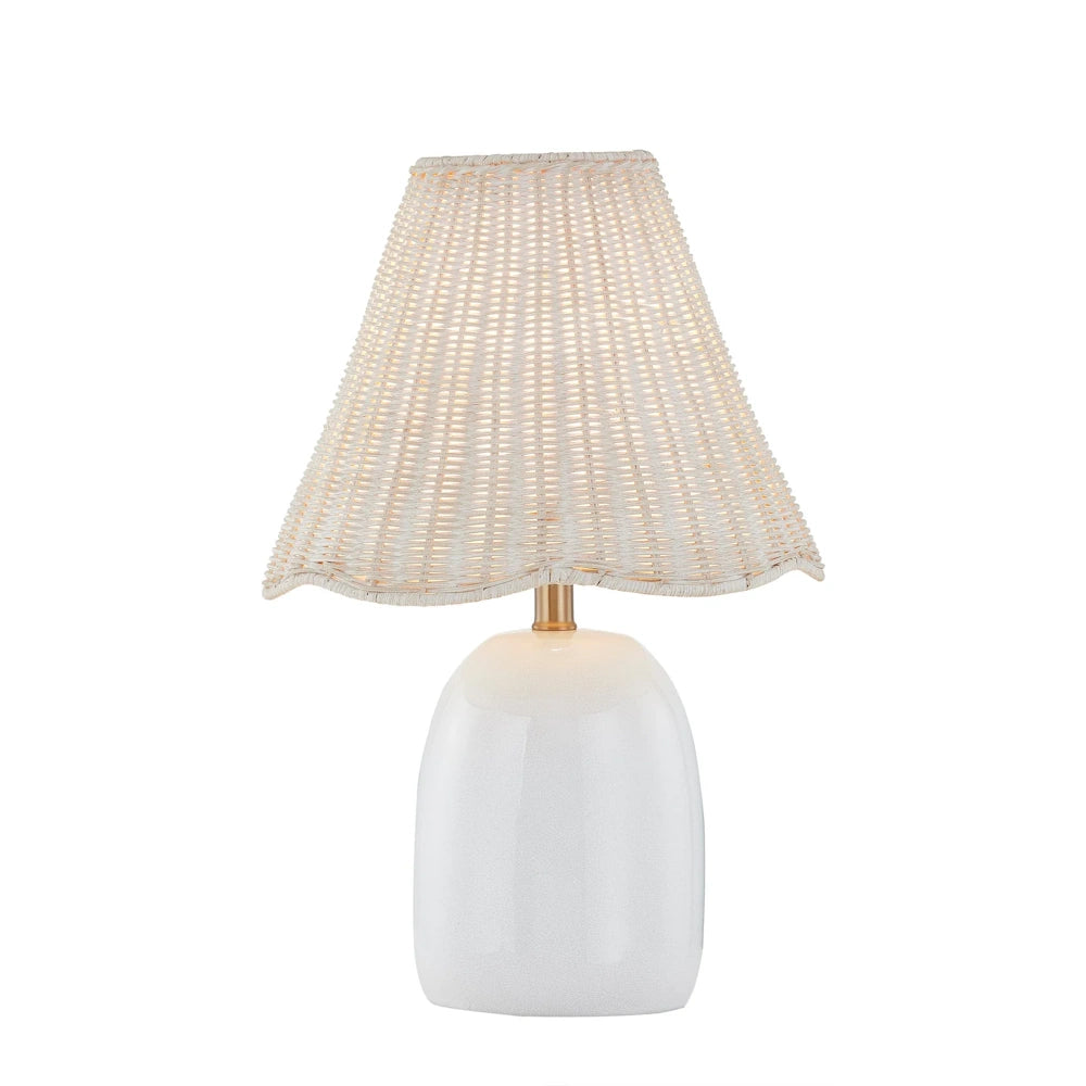 White ceramic table lamp with woven rattan shade, scalloped edge and brass accent for coastal decor.