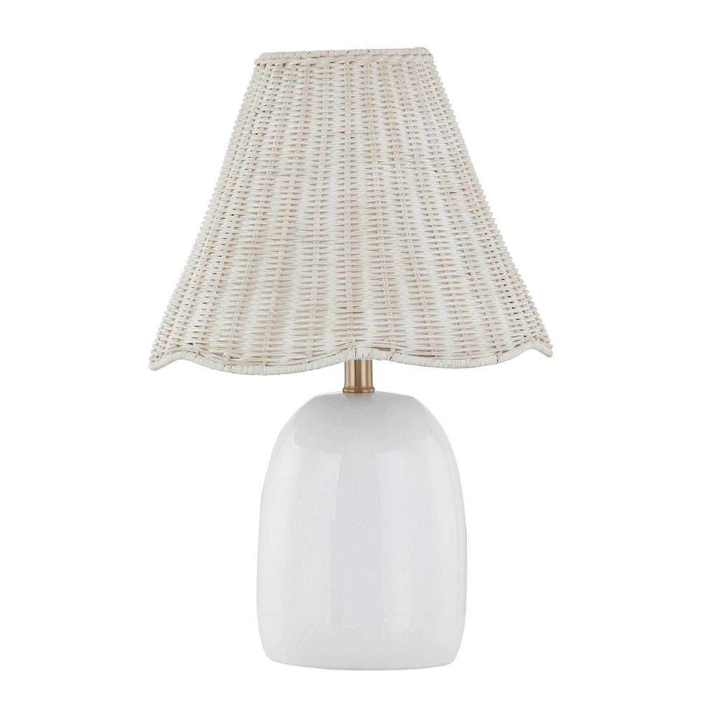 White ceramic table lamp with woven rattan shade, scalloped trim and brass accent for coastal decor.