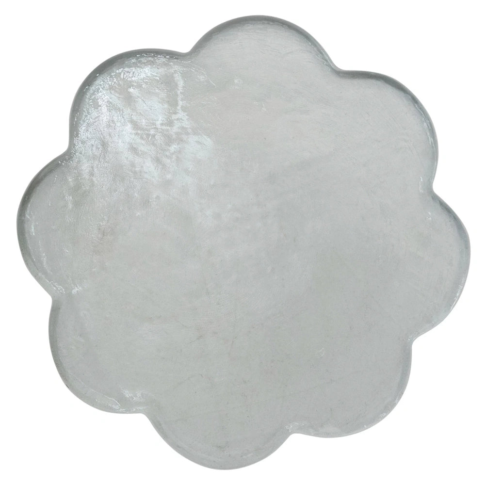 Top-down view of a clear pressed glass serving board with a scalloped, flower-shaped edge and a textured surface.