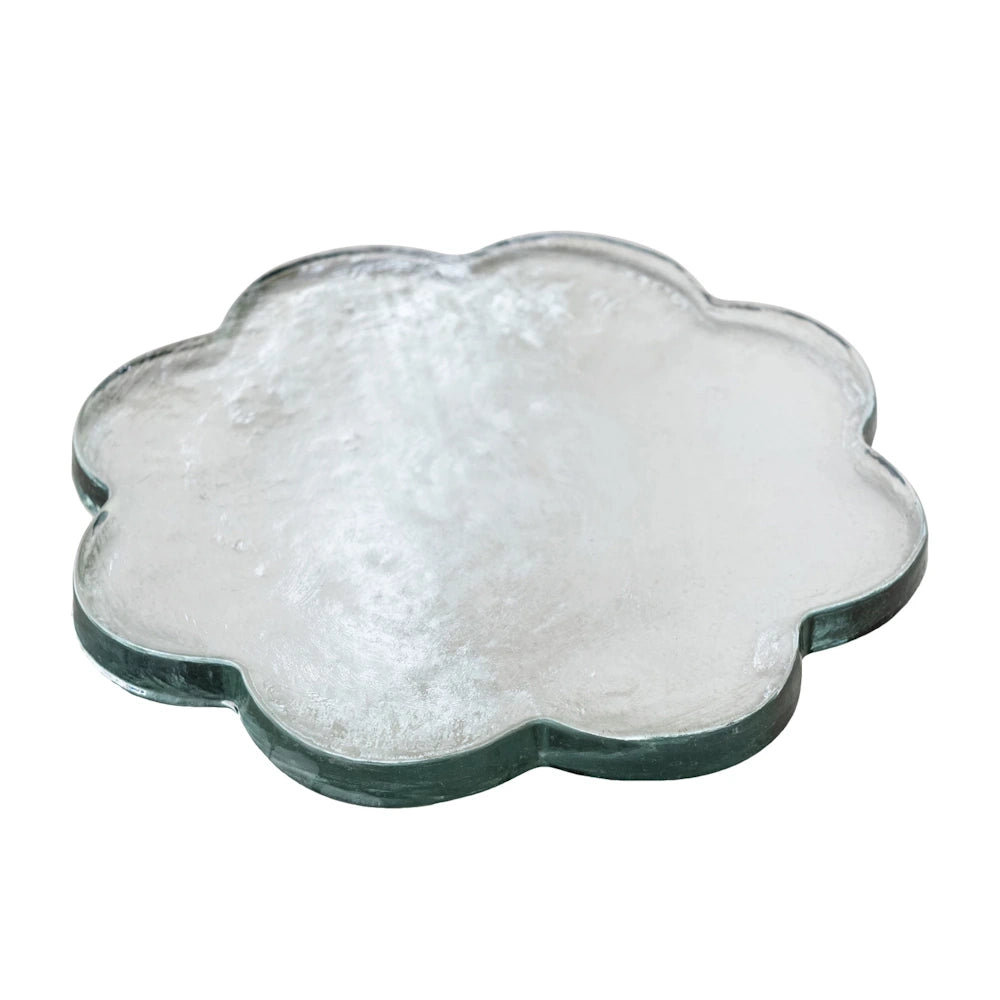 Angled view of a clear scalloped glass cheese board with a textured finish and flower-like silhouette.