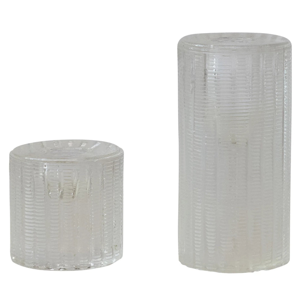 Two clear fluted pressed glass taper candle holders in small and large cylindrical sizes on a white background.