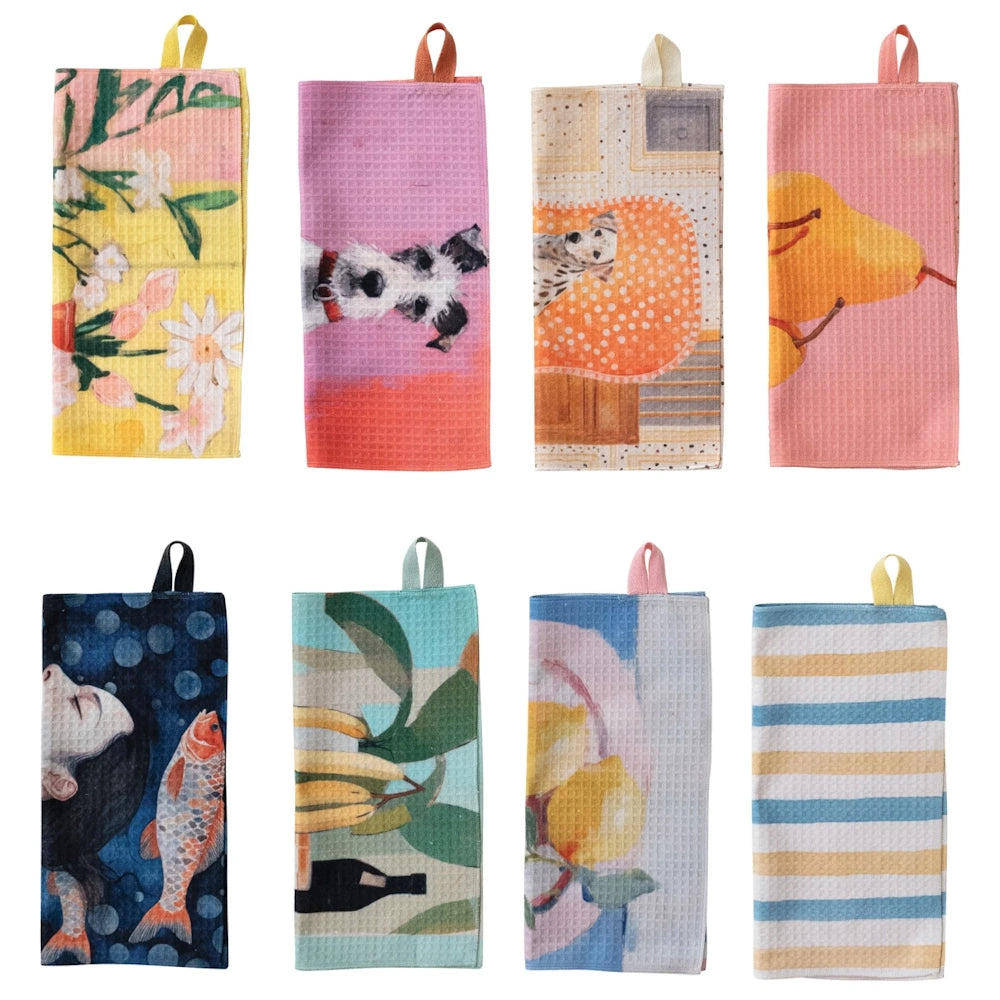 Assorted recycled microfiber tea towels featuring artistic prints of dogs, fruit, florals, and stripes with hanging loops.