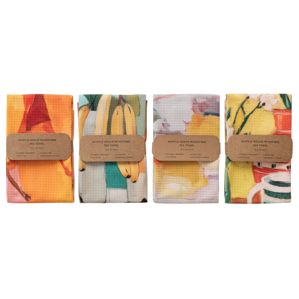 Four folded waffle-weave microfiber tea towels with colorful fruit and floral prints and eco-friendly paper packaging.
