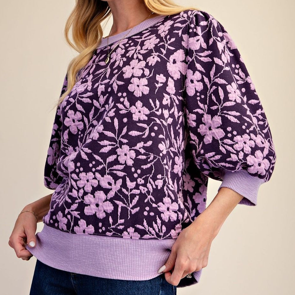 Dark purple textured sweatshirt with light purple floral pattern and puff sleeves.