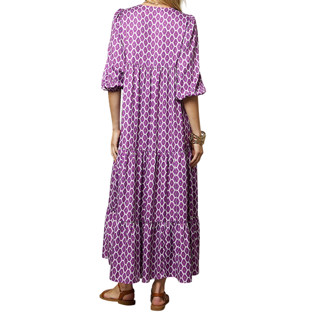 Rear view of a woman in a purple and white geometric print tiered maxi dress with puff sleeves.
