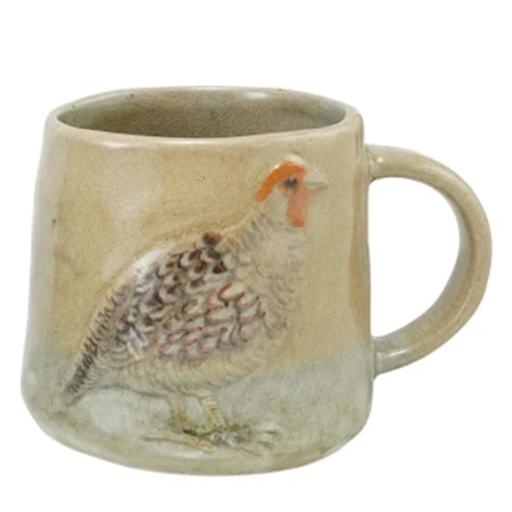A rustic stoneware mug featuring a hand-painted, embossed quail illustration on a neutral beige ceramic background.