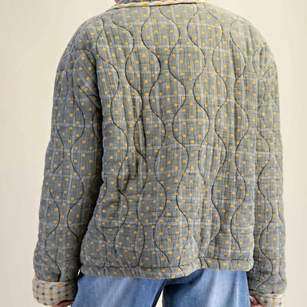 Back view of a mineral-washed green quilted jacket featuring a scalloped stitching pattern.