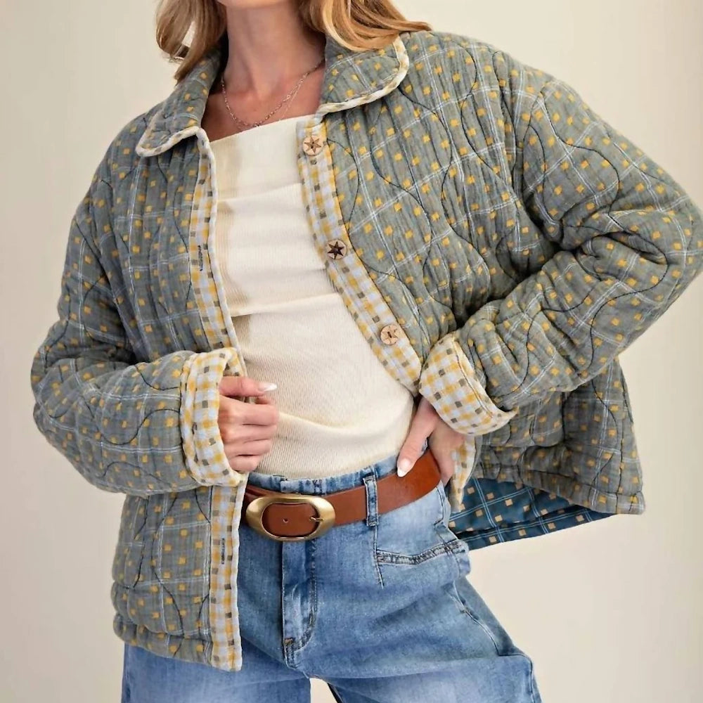 Front view of an open green mineral-washed quilted cotton jacket with a plaid pattern and brown belt.