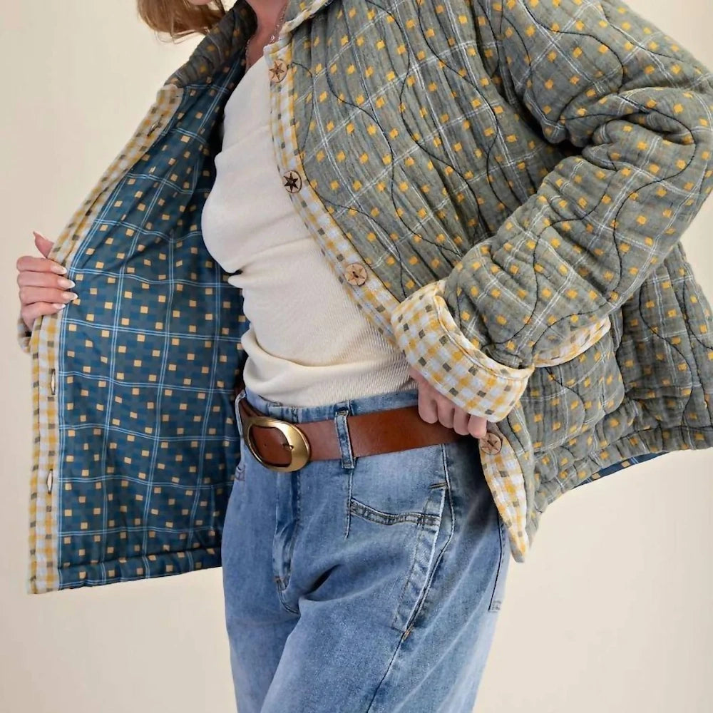 Side angle of a mineral-washed green quilted cotton jacket with a plaid inner lining.