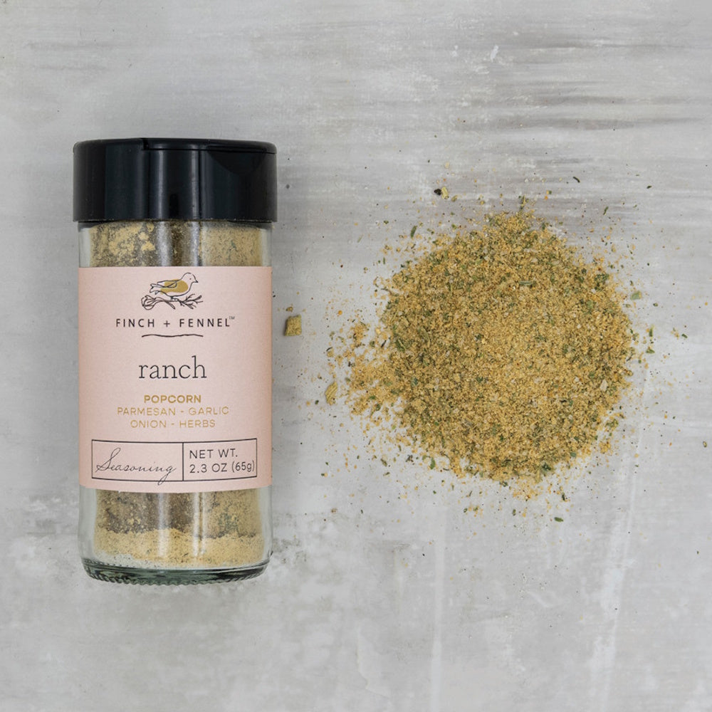 A jar of Finch & Fennel ranch popcorn seasoning next to a pile of loose seasoning, top-down view.