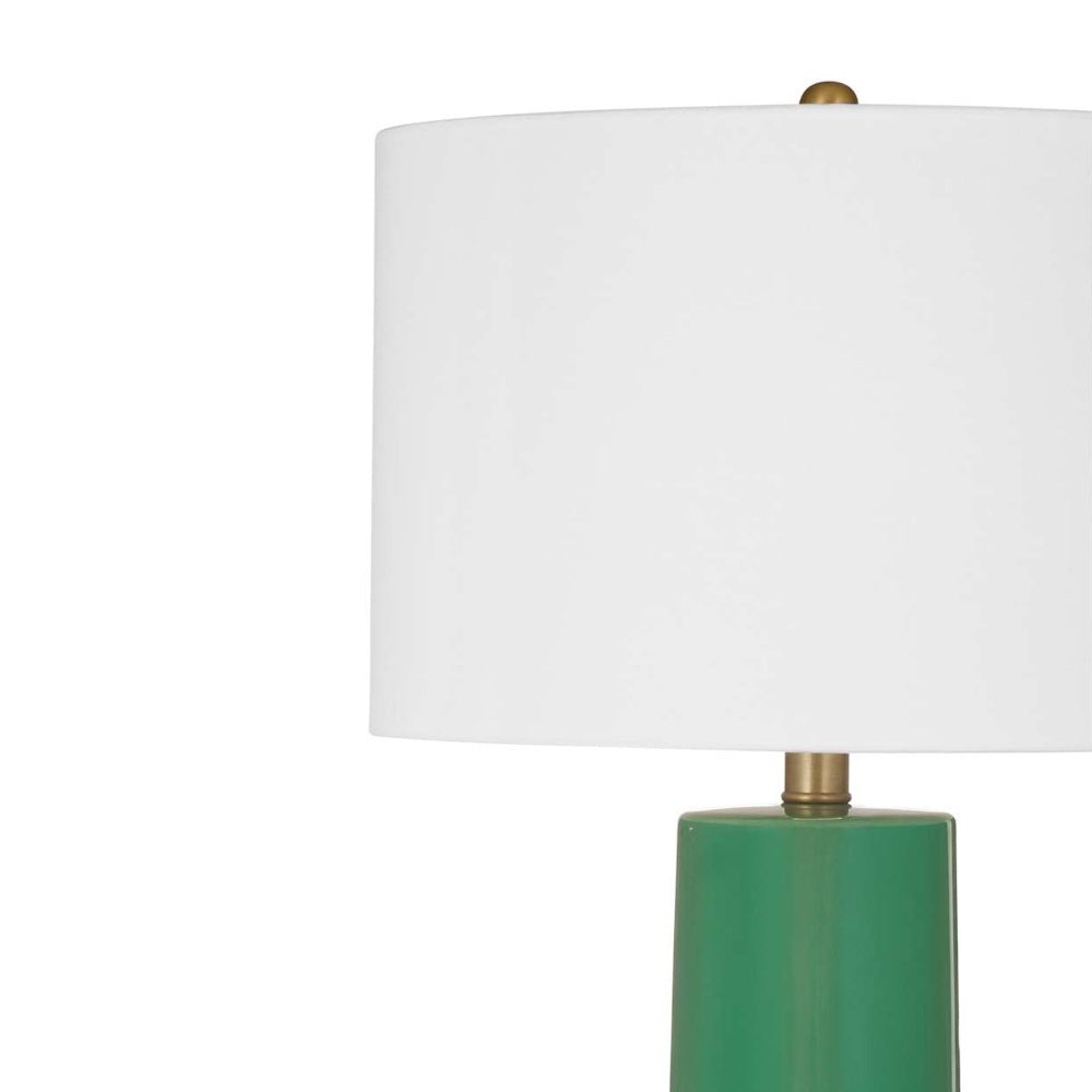 Close-up of a white drum lampshade with a brass finial atop a green ceramic base.