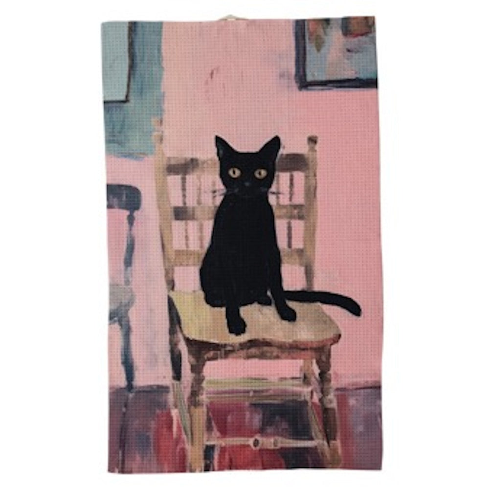 An illustration of a black cat with yellow eyes sitting on a wooden chair against a pink wall on a tea towel.