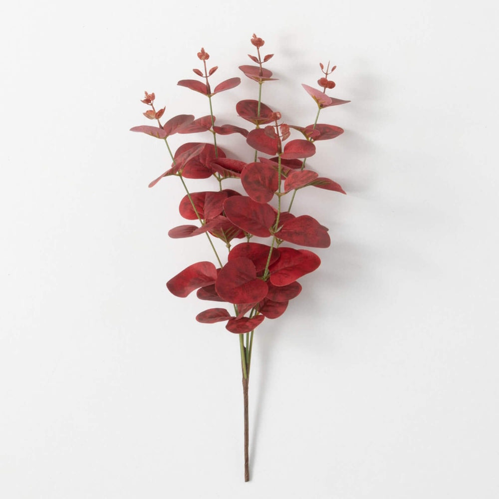 An artificial stem of red eucalyptus with rounded leaves on multiple small branches against a white background.