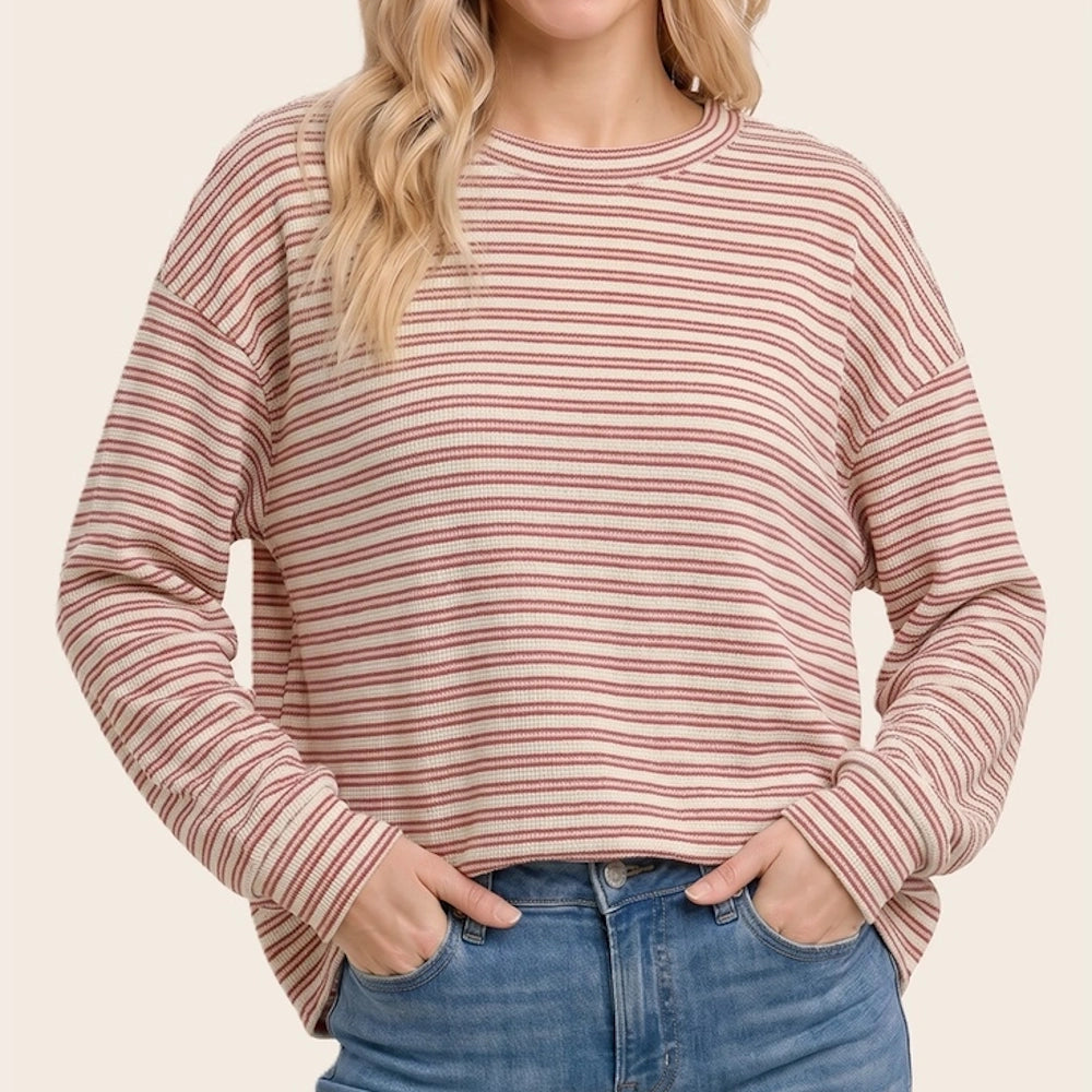 Red and off-white fine horizontal striped long-sleeve crewneck top worn with blue jeans.