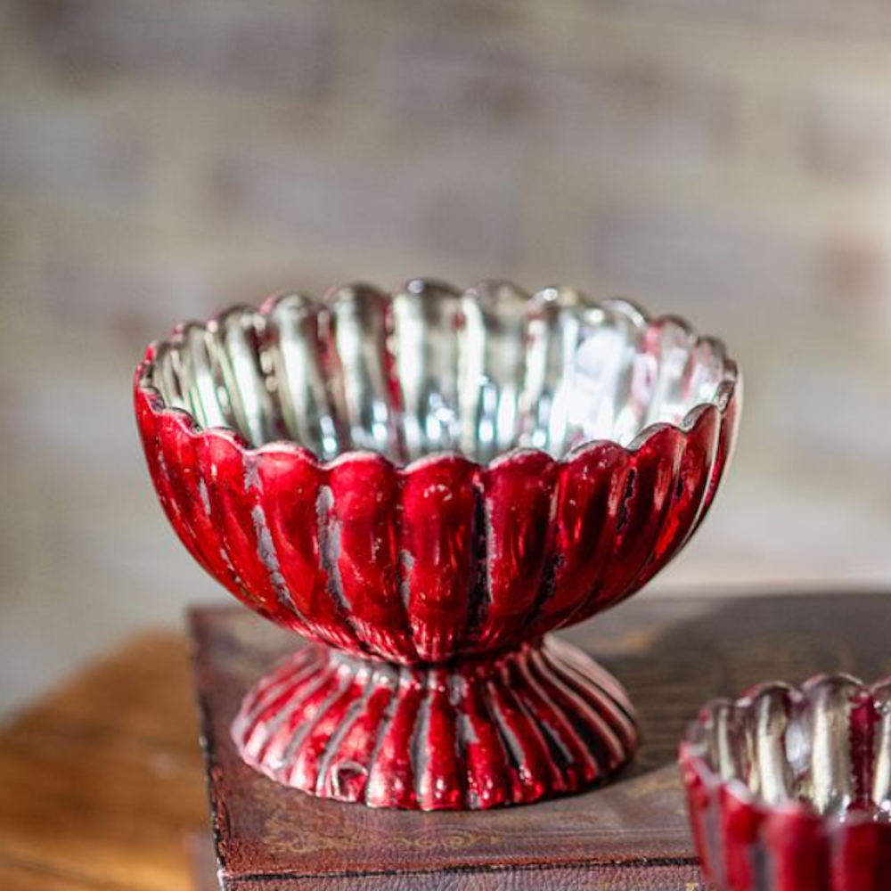A small, distressed red mercury glass pedestal bowl with scalloped, ribbed edges.