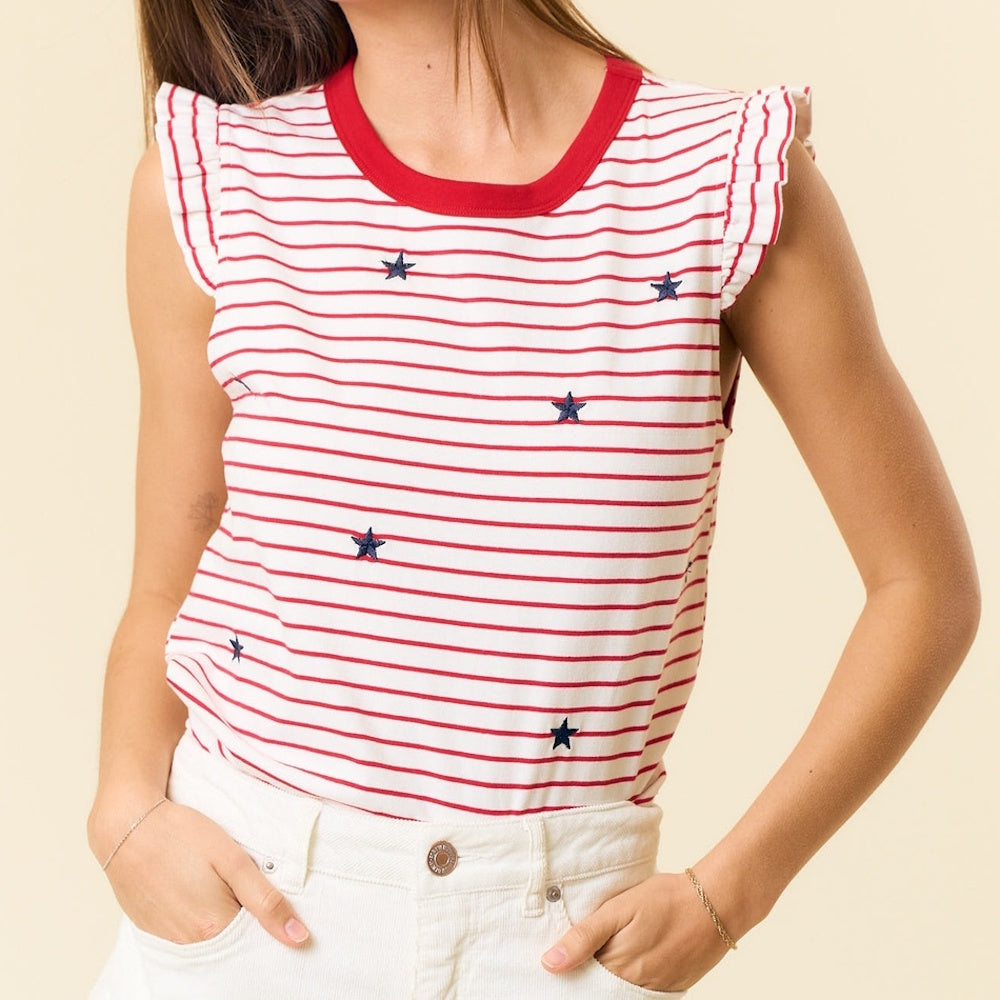 A woman wearing a red and white striped sleeveless top with small embroidered blue stars and ruffle shoulders.