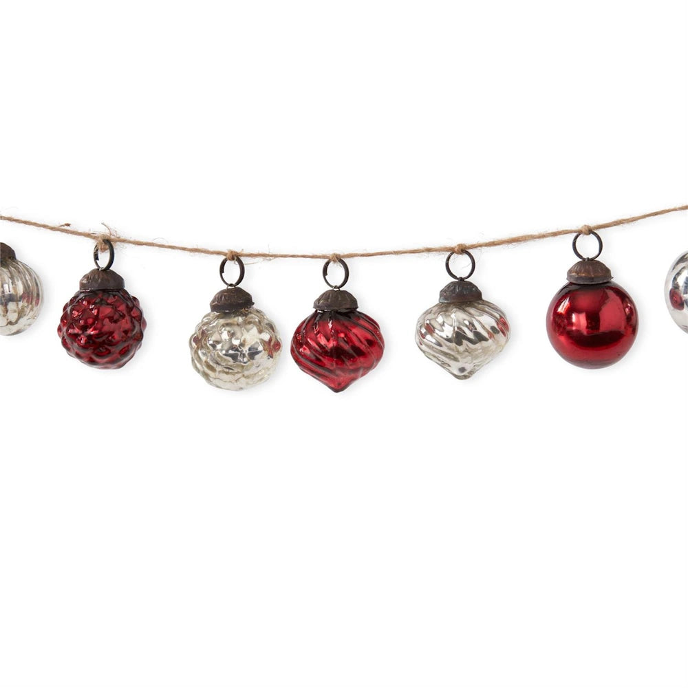 Garland of assorted red and silver glass Christmas ornaments hung on twine.