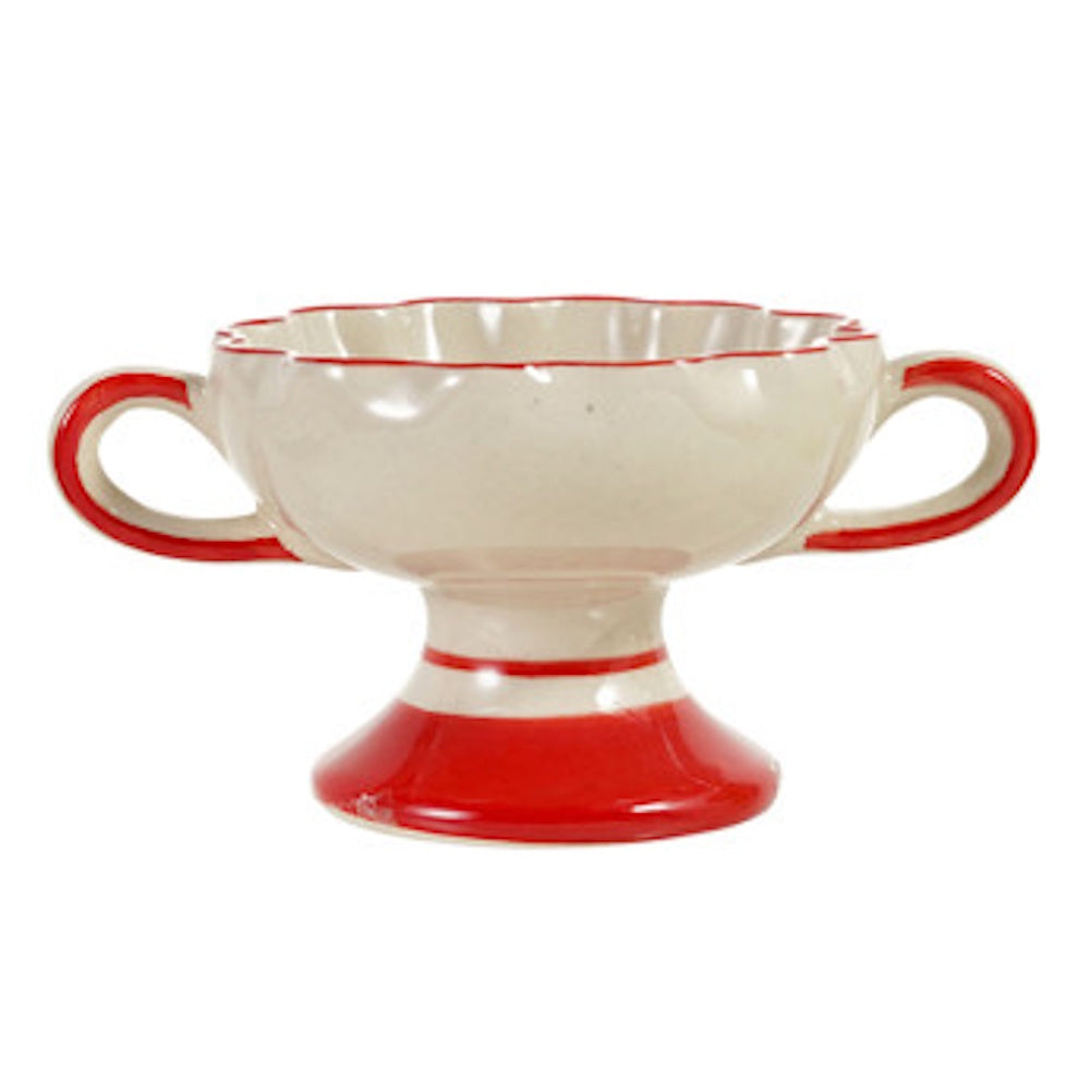 Scalloped ceramic footed bowl in cream with red handles and trim on a white background.