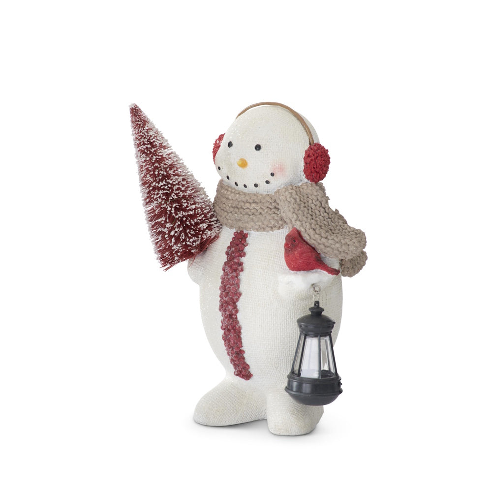 Side profile of resin burlap-textured snowman holding a red bottle brush tree, cardinal, and lantern.
