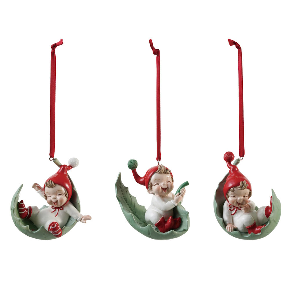 Three resin elf ornaments hanging by red ribbons in green leaf-shaped cradles.