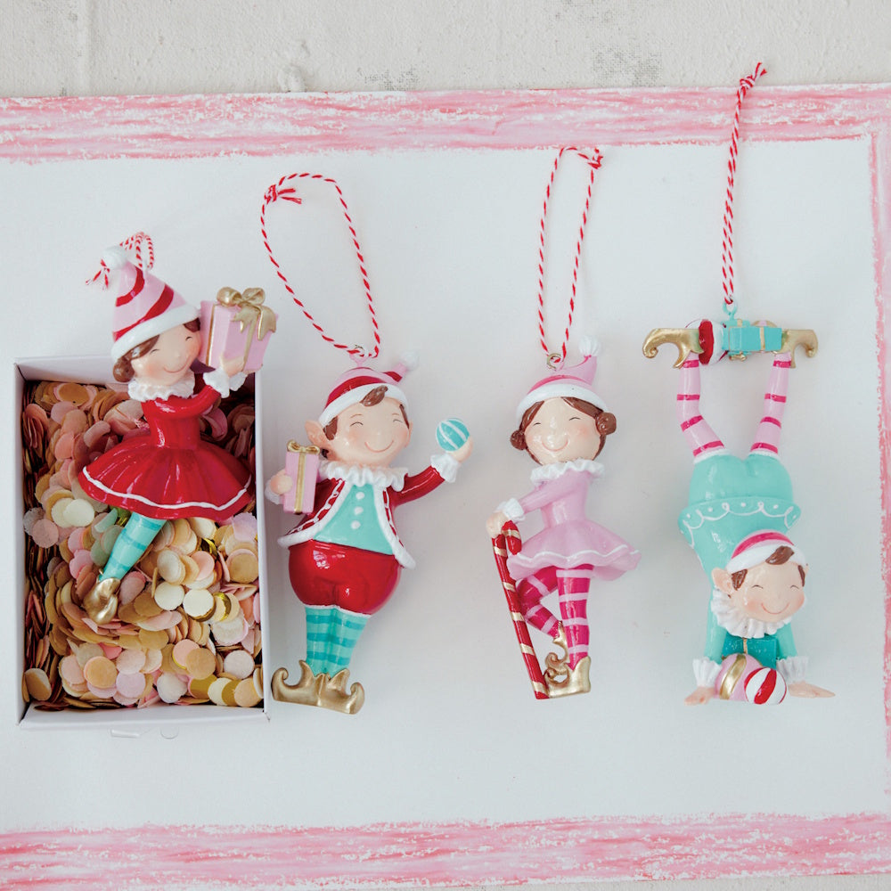 Four colorful Christmas elf ornaments displayed side by side with red-and-white baker's twine.