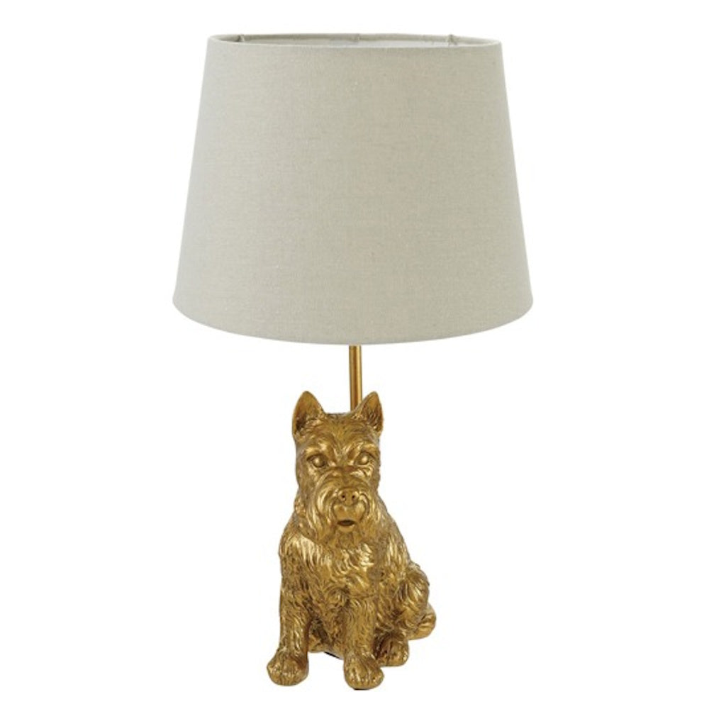 Gold Scottie dog-shaped table lamp with a neutral drum shade, isolated on a white background.
