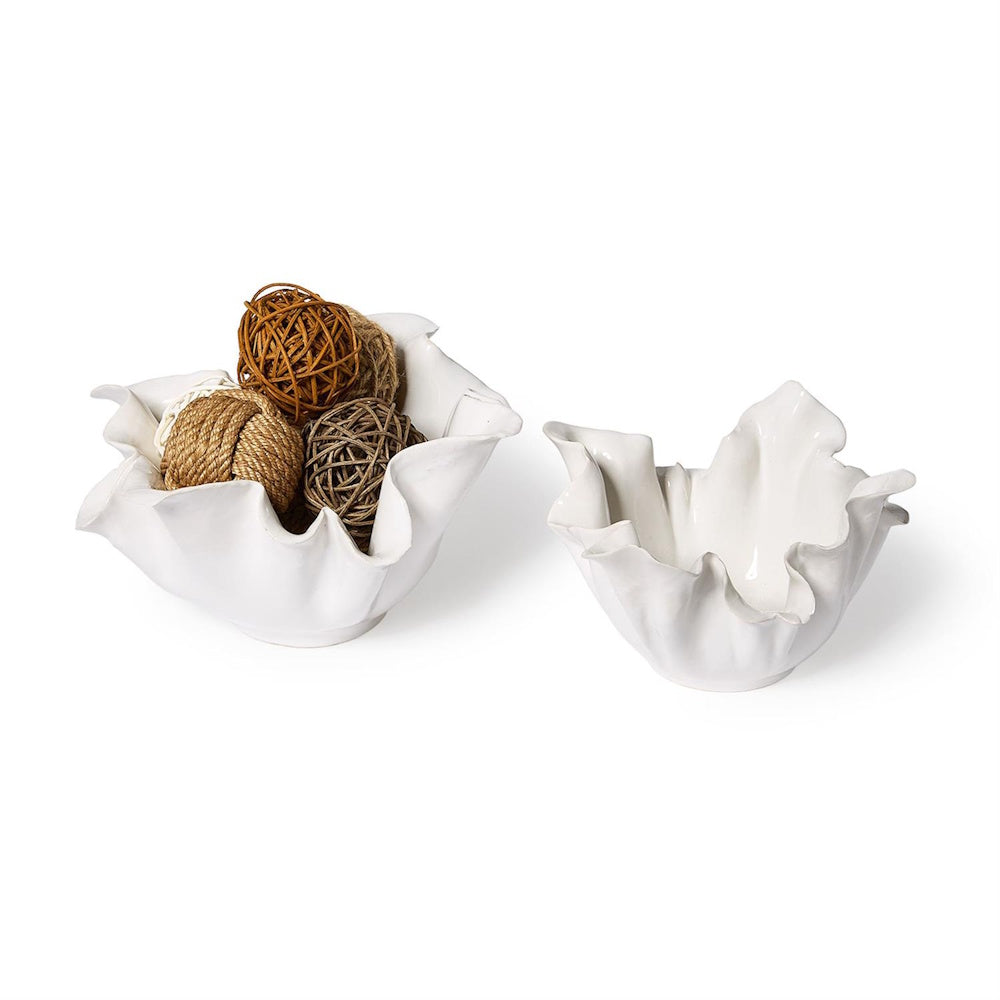 Two ruffled white ceramic bowls on a white surface, one filled with decorative woven rattan spheres.