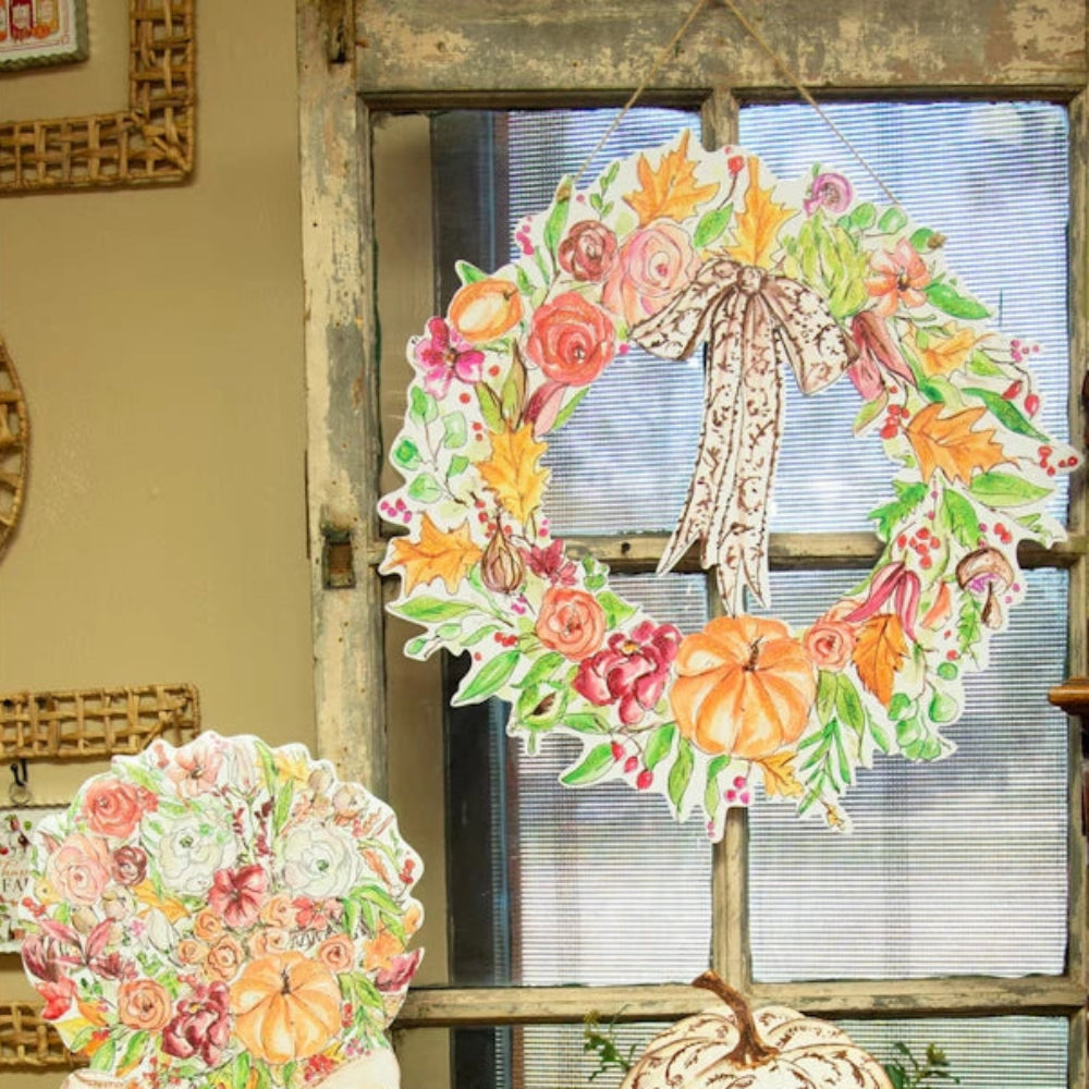 Watercolor autumn decor featuring a floral wreath, topiary cutouts, and a pumpkin in a basket.