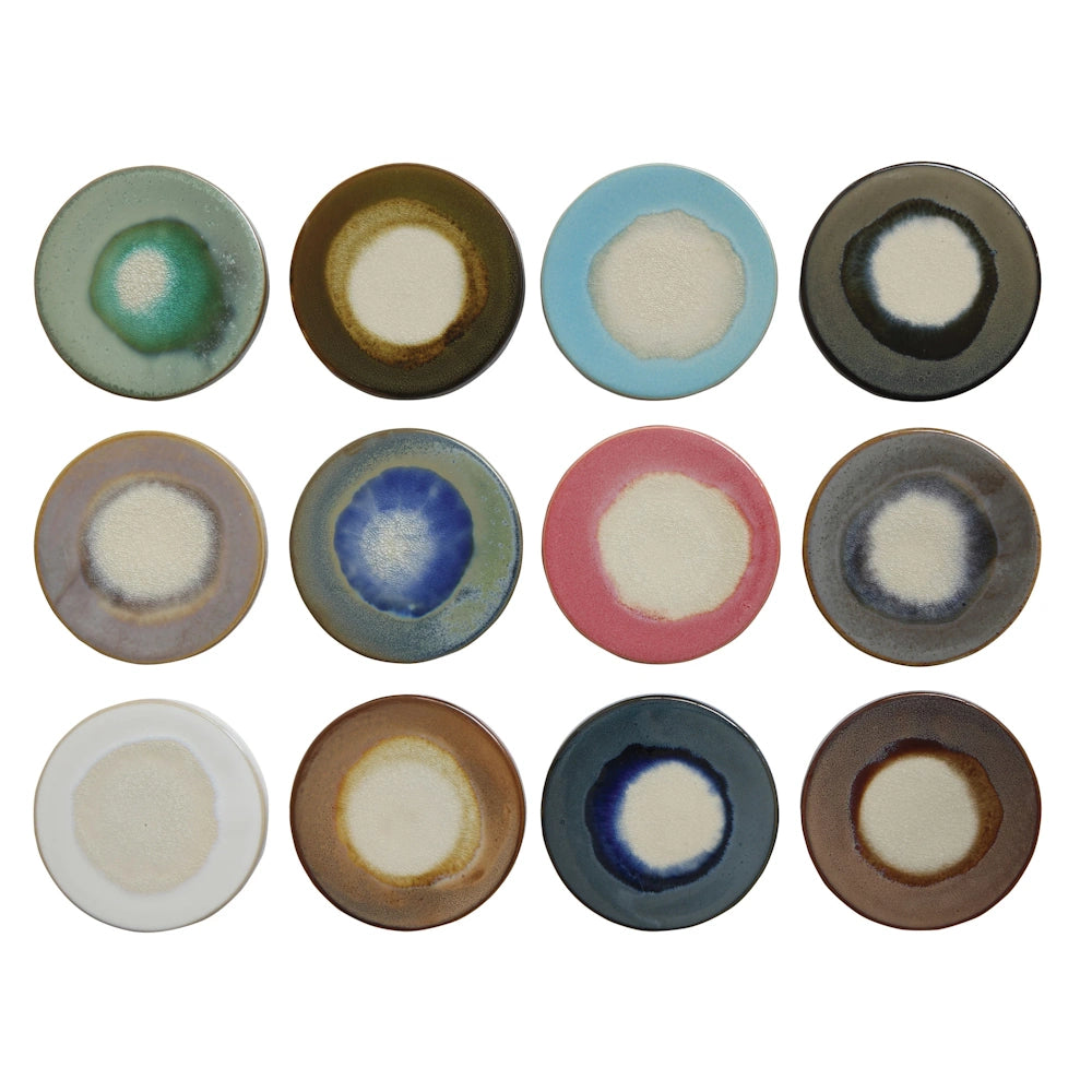 Set of 12 round stoneware trivets with colorful reactive glaze finishes in blue, pink, green, and earth tones.