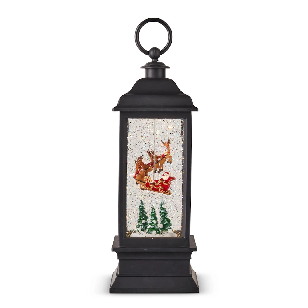 A black animated lighted water lantern featuring Santa in a sleigh with reindeer flying over snow-covered trees.