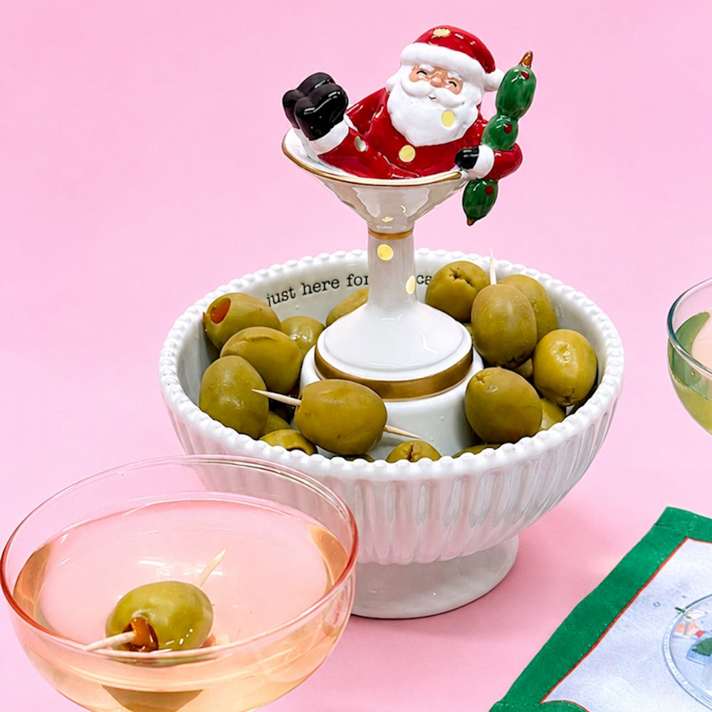 Ceramic Santa in a martini glass figure resting inside a pedestal bowl filled with green olives.