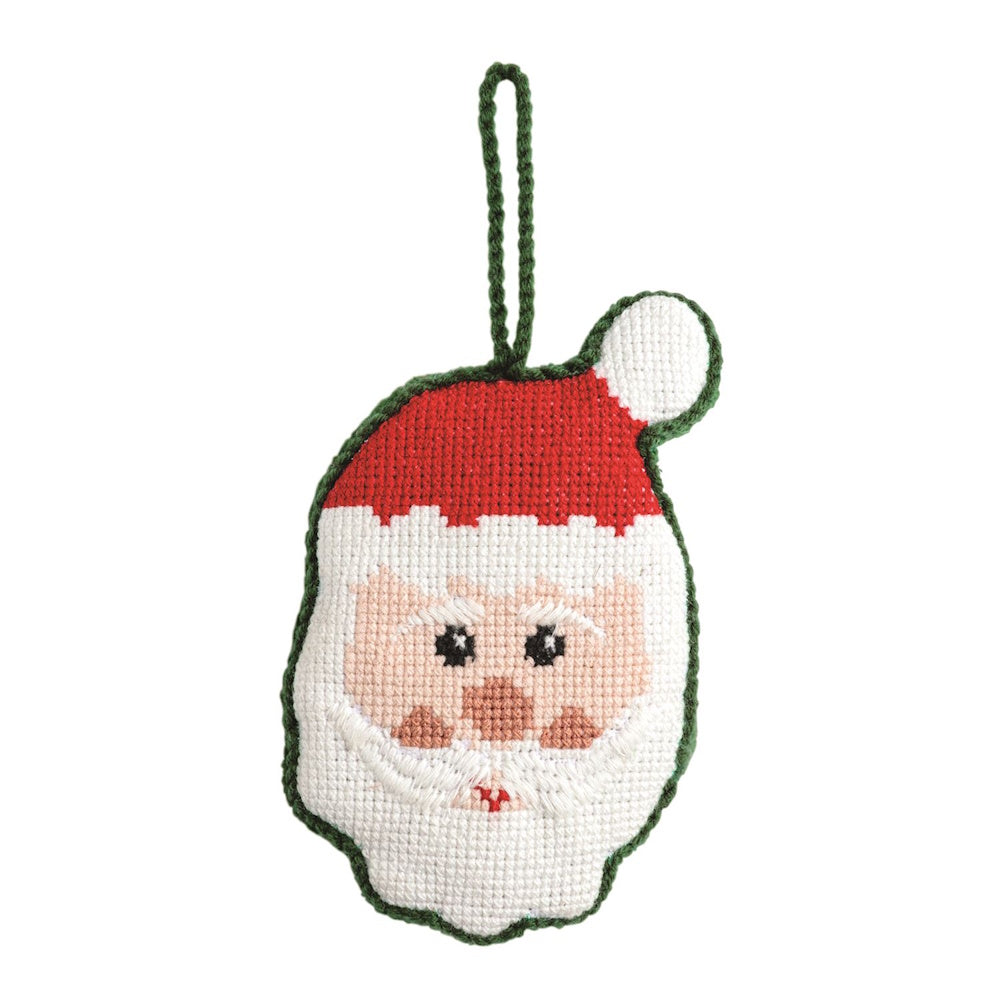Handcrafted needlepoint Santa Claus face ornament with a red hat and green trim on a white background.