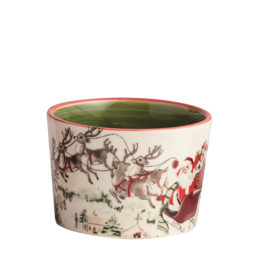Front view of a white ceramic Christmas tidbit dish featuring a painted design of Santa and reindeer flying over a snowy village.