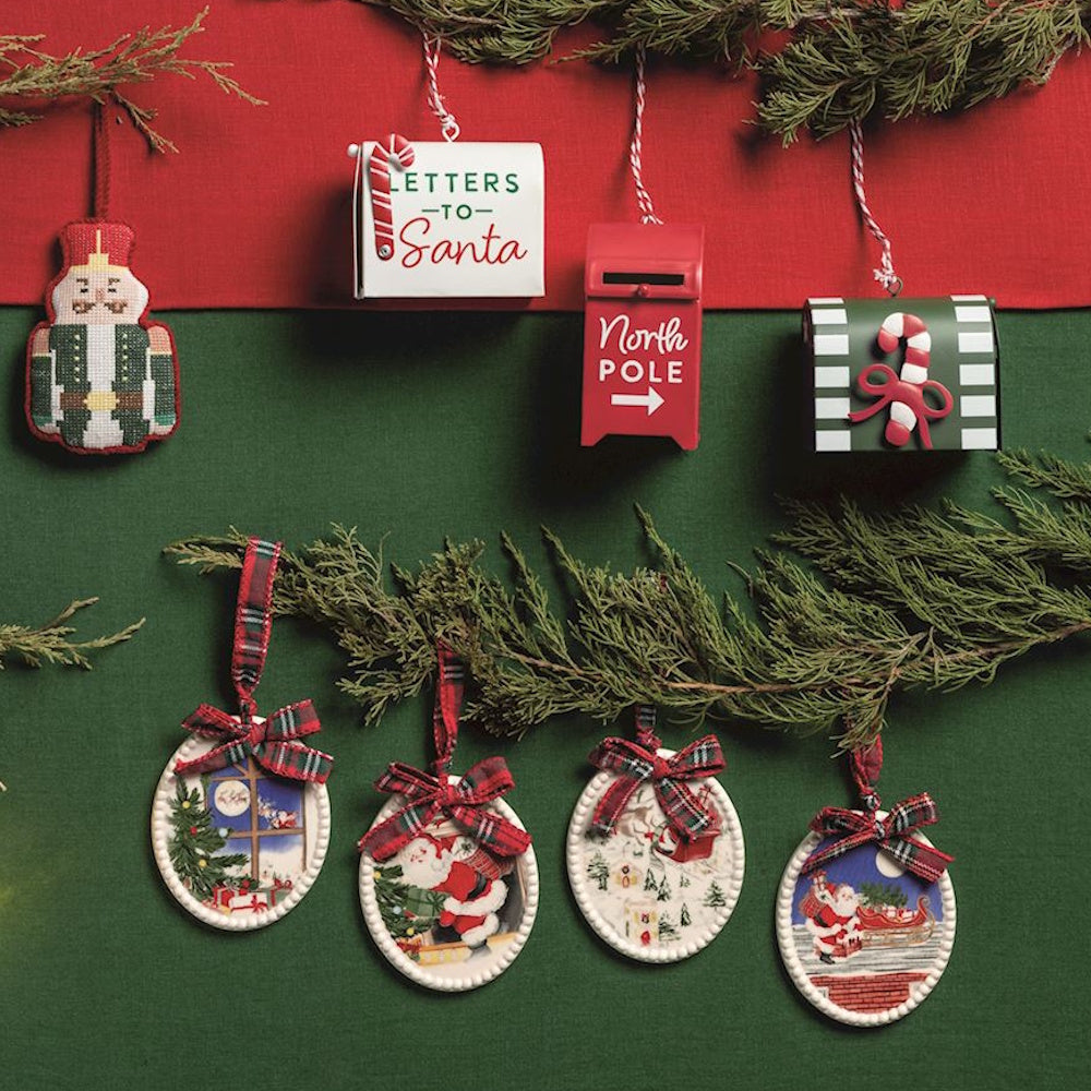 Assorted Christmas ornaments, including oval Santa scenes and mailboxes, against a green backdrop.