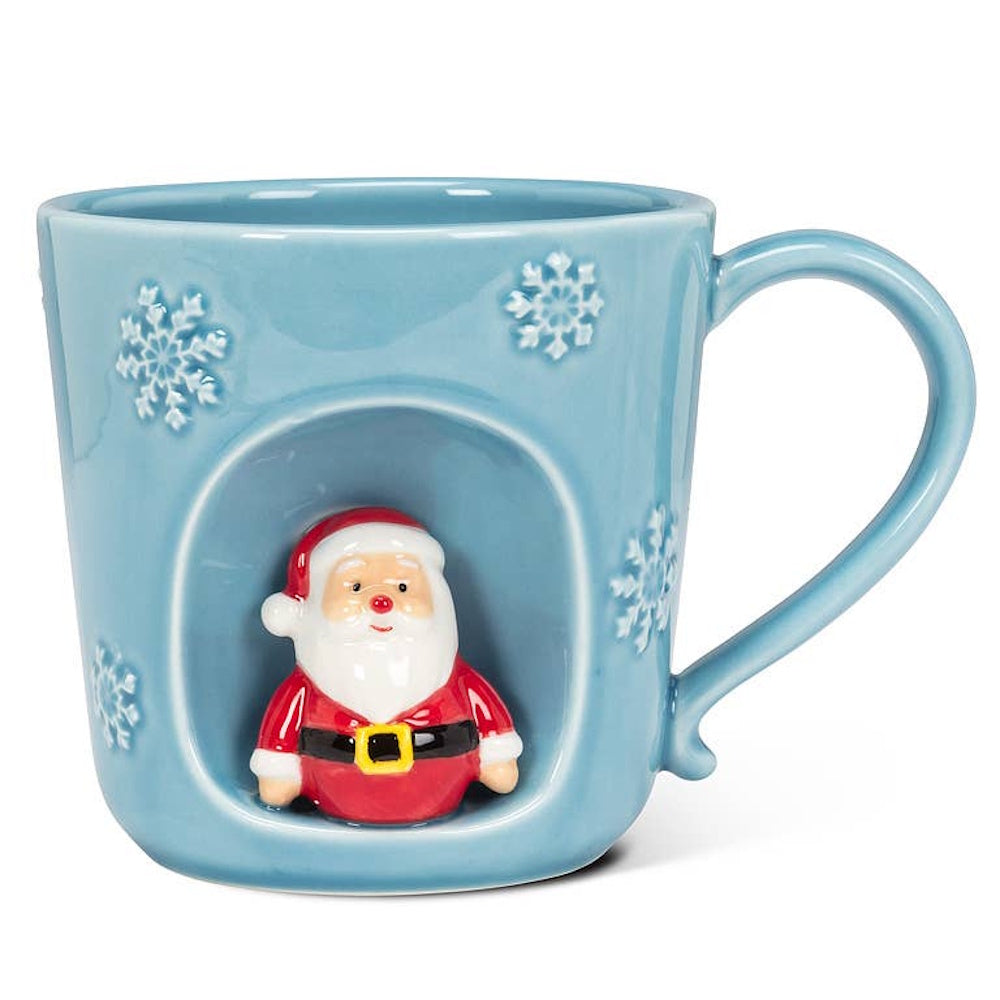 Light blue ceramic mug decorated with snowflakes and a 3D Santa Claus figure inside an inset arch.
