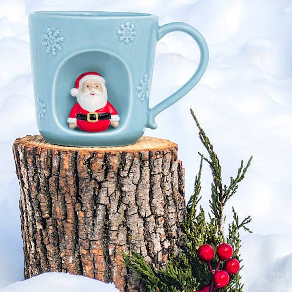 Light blue snowflake mug featuring a miniature Santa Claus figurine set inside a front alcove.