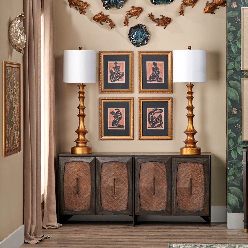 Modern wood sideboard with gold pedestal lamps, framed figure art, and decorative fish wall sculptures.