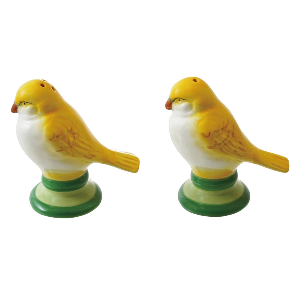 Yellow and white ceramic bird salt and pepper shakers on green pedestals, vintage-style kitchen tabletop decor.
