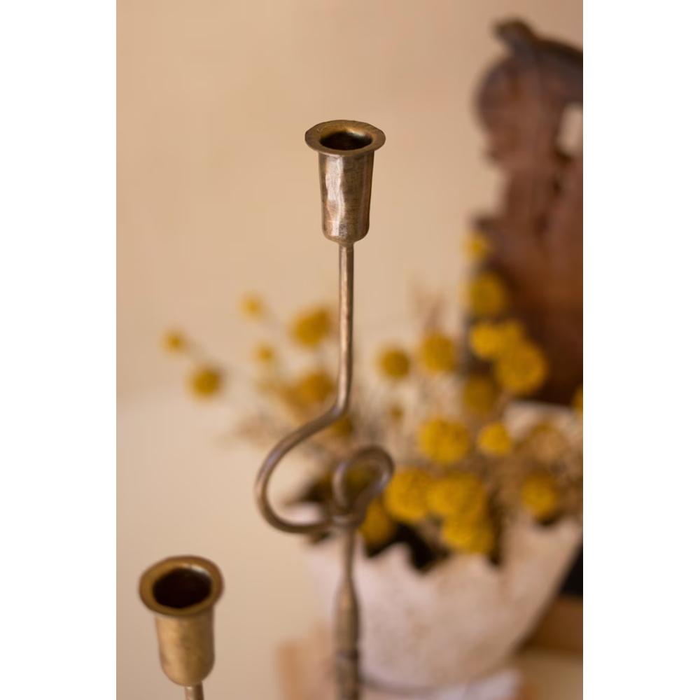 Detailed view of empty candle cups and looped stems on antique brass forged iron candleholders.