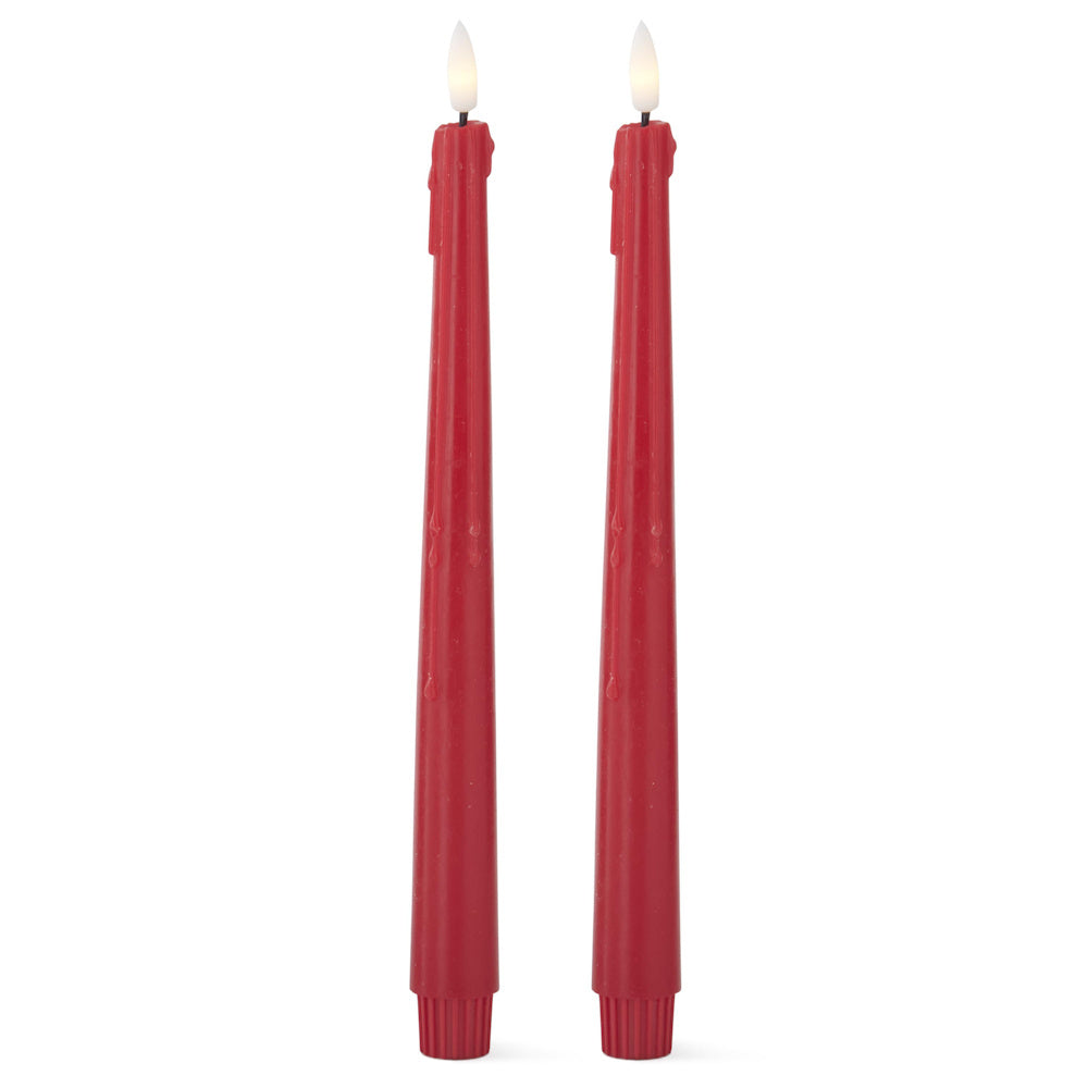 Two tall, red flameless taper candles with faux dripping wax and lit LED flames against a white background.