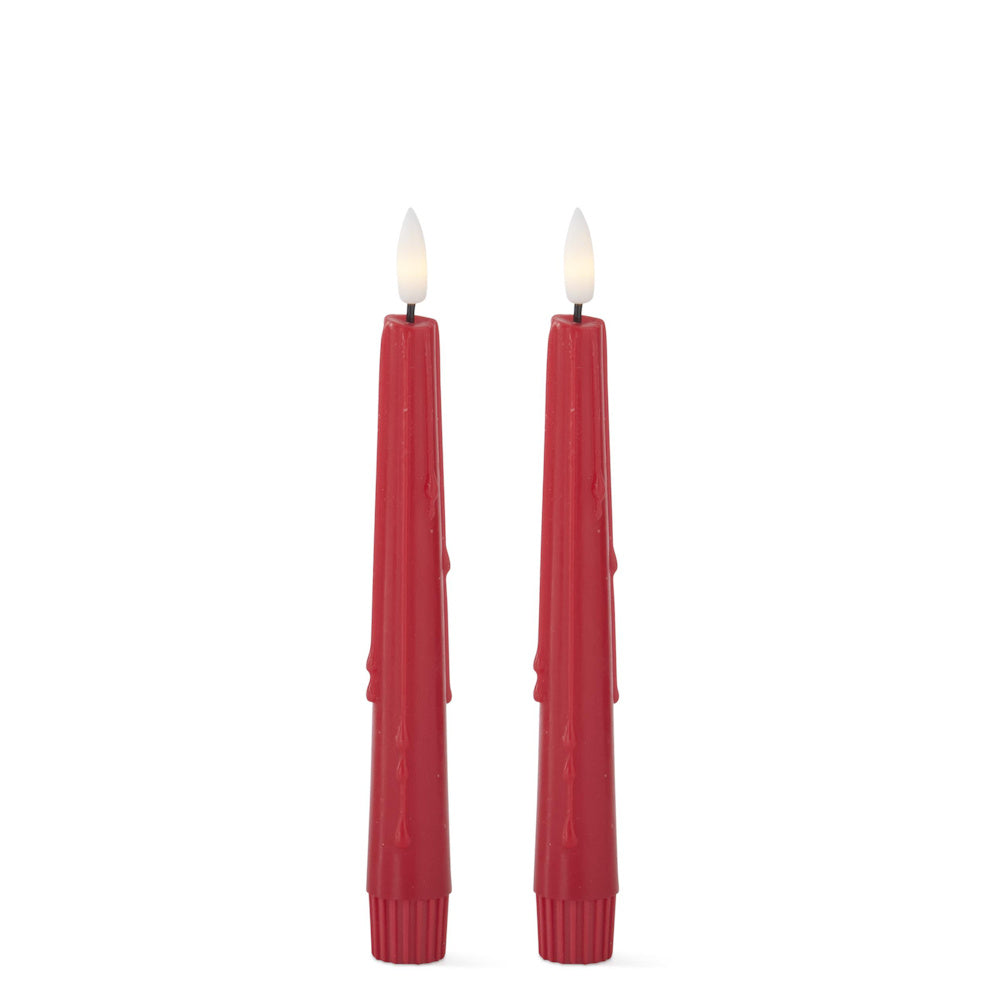 Two tall red taper candles with faux dripping wax and glowing white flame tips against a white background.