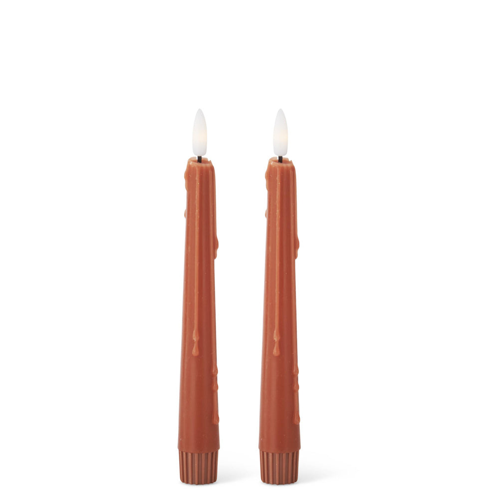 A pair of rust LED taper candles with a realistic faux wax drip design against a white background.